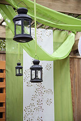 transforming an existing arbor, outdoor living, We took the same green panels and hung them from the back to create a colorful back drop for our hanging lantern display Use varied sized lanterns to create a unique playful theme