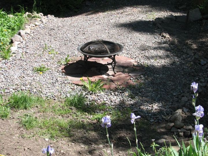 transforming a wilderness into a garden, decks, gardening, landscape, outdoor living, ponds water features, Instead of one huge hillside I have now 3 levels One running alongside the deck and sun room with the Iris and a little pathway installed One beneath that with a fireplace I just don t like the gravel and so I am in the process of removing it and I will sow grass instead Easier to maintain simply moving it then plucking weeds out of the gravel