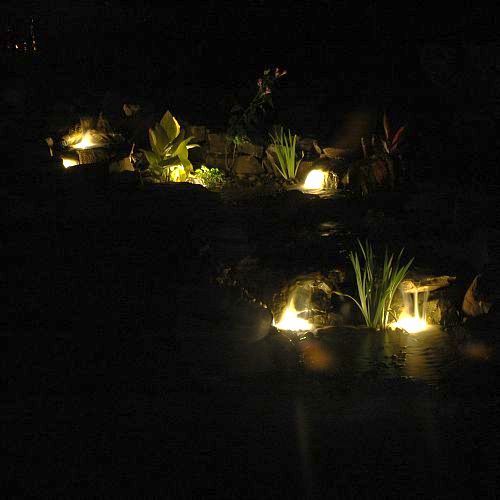 underwater lighting creates a nighttime oasis for water feature owners, landscape, lighting, outdoor living, ponds water features, Lighting under waterfalls really accents each individual falls At night it s fun to watch the water rushing over the edge past the light