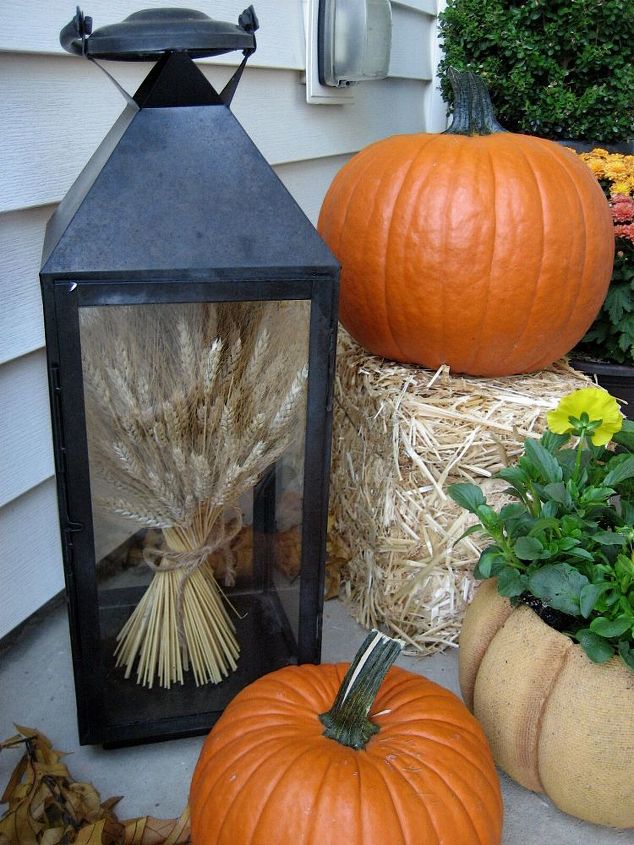 my front porch for fall pumpkins fall flowers lanterns and a fun corn garland, curb appeal, flowers, home decor, seasonal holiday decor, A lantern filled with wheat welcomes my guests