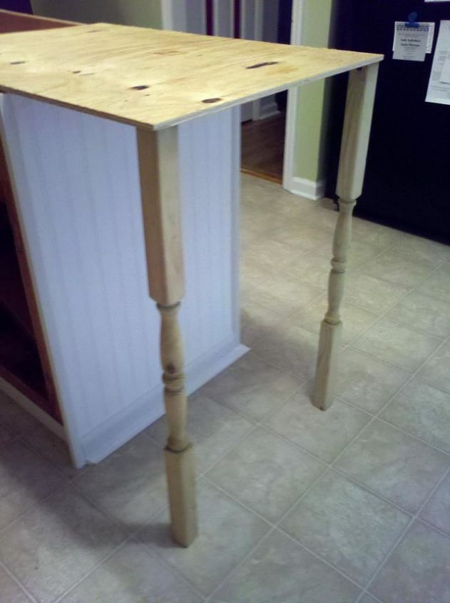 old base cabinets repurposed to kitchen island, I got some outdoor deck posts to use for legs which were much cheaper than other leg options they just needed extra sanding This is just getting an idea how they will look