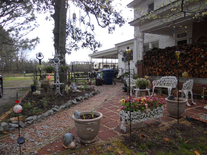 flower gardening turning a dead area into a southern style courtyard, decks, flowers, outdoor furniture, outdoor living, New Courtyard After raking up tons of leaves we found lots of roots from the magnolia tree We hauled in dirt and sand leveled the yard and begin placing 12x12 blocks A walkway was made with repurposed bricks from a home that was torn down The gravel between the bricks and the blocks was left over from another project We scavenged the rocks from a relocated house site Many of the flower pots were found at yard sales A 2 seater swing allows us a place to enjoy our morning coffee