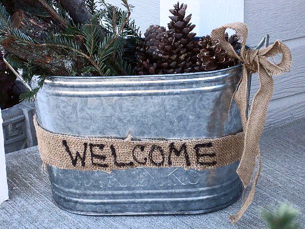 winter front porch decorating, crafts, seasonal holiday decor, Galvanized bucket display on my front porch The pine springs logs and pine cones with a little burlap bow just make me smile