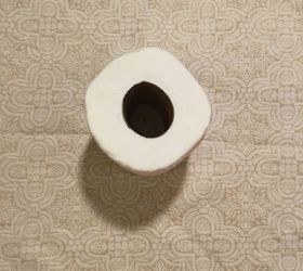 A woman tucks fabric into toilet paper for a 10-second fall bathroom idea