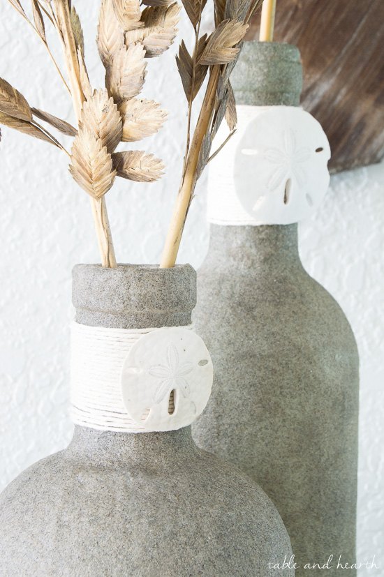 31 coastal decor ideas perfect for your home, Repurpose Bottles Into Vases Coated In Sand
