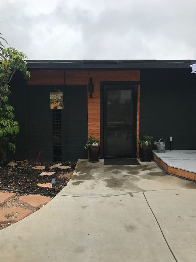 como modernizar uma casa com cor preta, Porta preta cercada por madeira