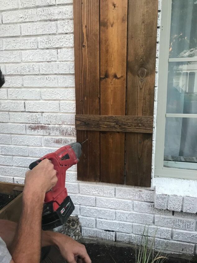 how to hang wood shutters on brick, drill going into wood shutter on white brick house