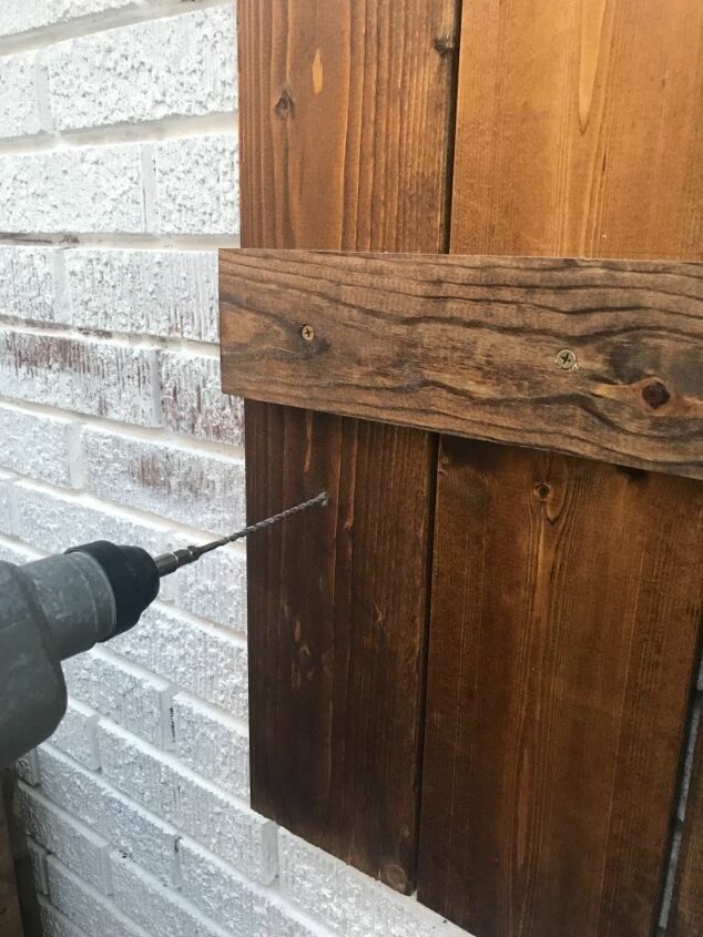 how to hang wood shutters on brick, drilling pilot holes into brick behind wood shutters