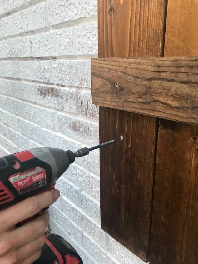 how to hang wood shutters on brick, drill inserting anchors into brick through wood shutter
