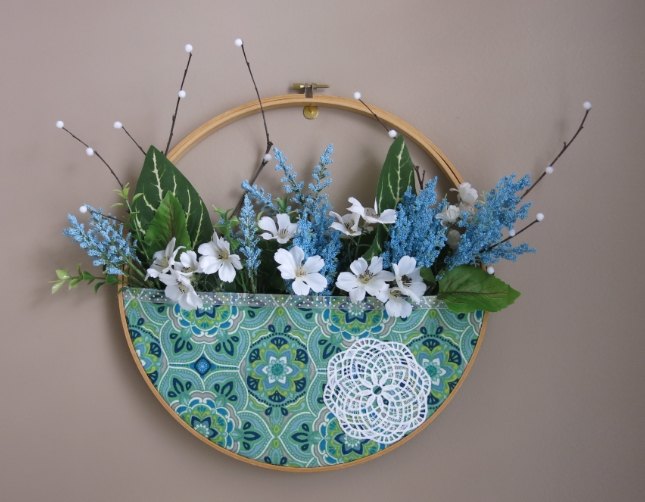 s 19 surprising ways to turn plain embroidery hoops into home decor, Add a touch of charm with a round floral pocket wreath