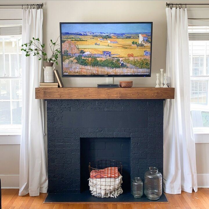 s 20 fireplace makeovers that will get your home in shape for the cold, Upgrade an old fireplace with a bold coat of paint and a sleek wooden mantel