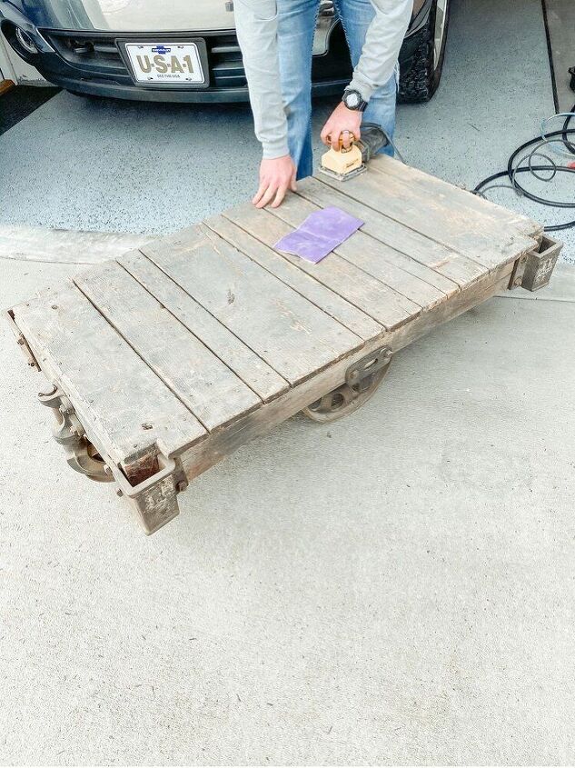 how to restore an old railroad cart into a coffee table, Hubs just starting to sand it down