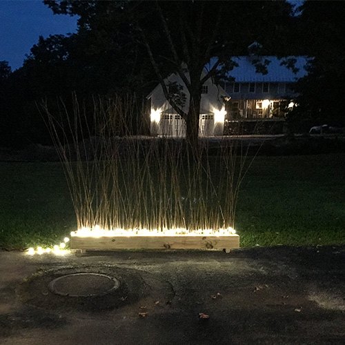 14 maneras de hacer que tu casa brille con luces de hadas, Haz una valla de privacidad iluminada con ramas de Ikea