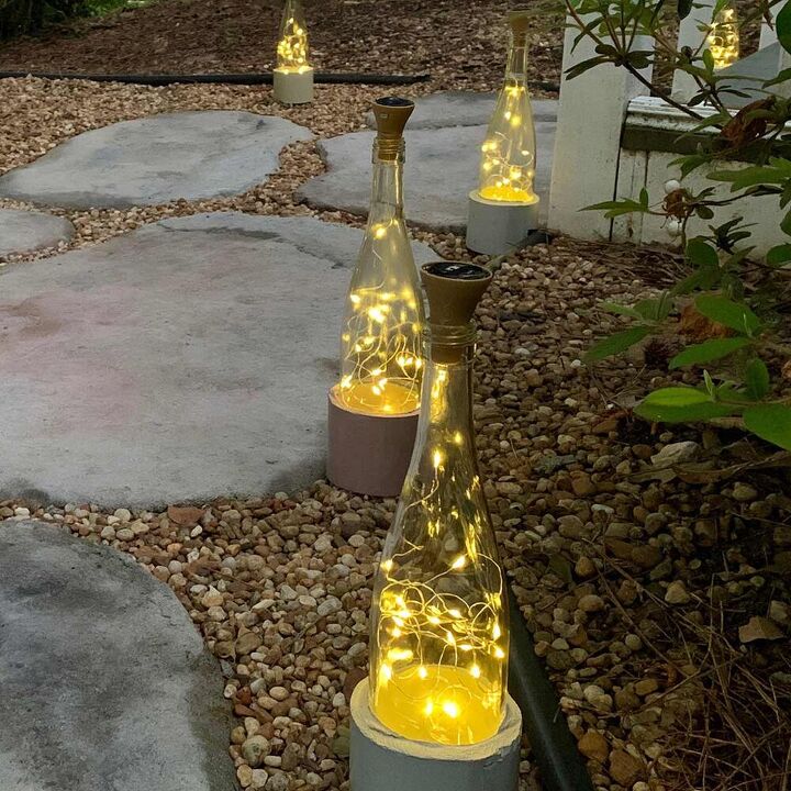 14 maneras de hacer que tu casa brille con luces de hadas, Luces para botellas de vino DIY con bonitas bases de cemento
