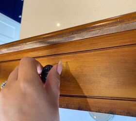 She takes the knobs off the fake drawers on this table to give it a breathtaking new look