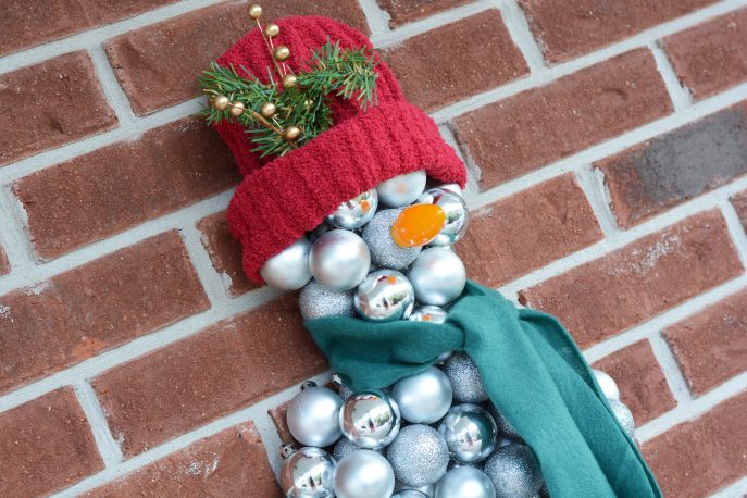 como hacer una facil decoracion de pared de un muneco de nieve con adornos navidenos