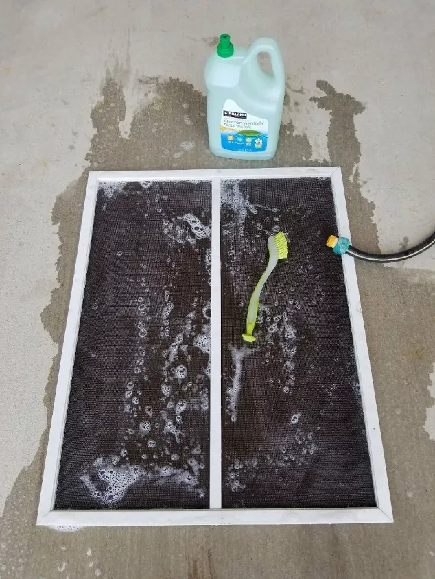 how to clean window screens like a pro, wet and soapy window screen on concrete