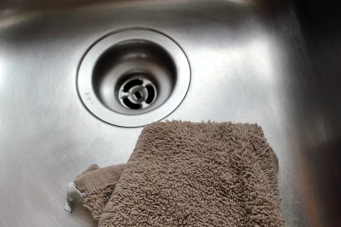 how to clean a stainless steel sink so it sparkles, brown towel in clean stainless steel sink