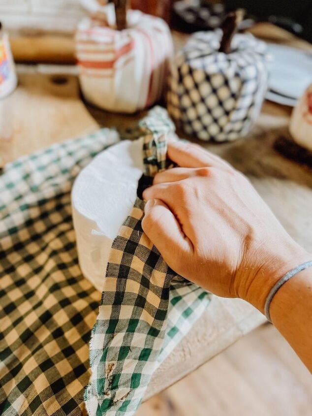 dale a tu hogar un toque otoal con estas decoraciones de calabazas, Mano envolviendo un rollo de papel higi nico con tela