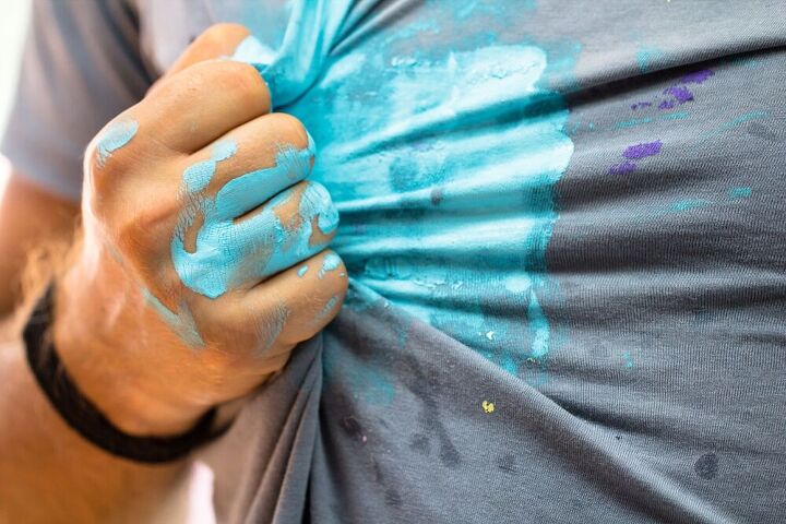 don t panic here s how to get paint out of clothes, Hand pulling gray shirt covered in blue paint