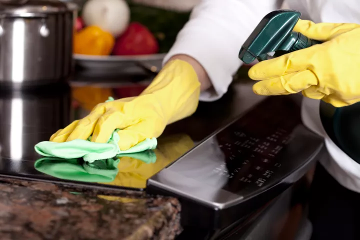 how to quickly clean your house from top to bottom, Person cleaning kitchen countertop