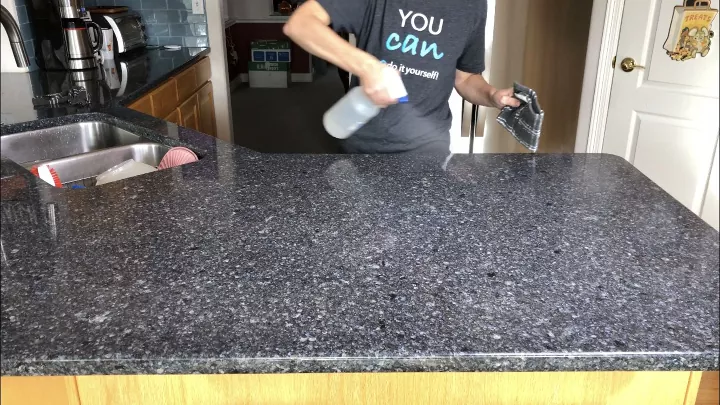 how to quickly clean your house from top to bottom, Person spraying countertop