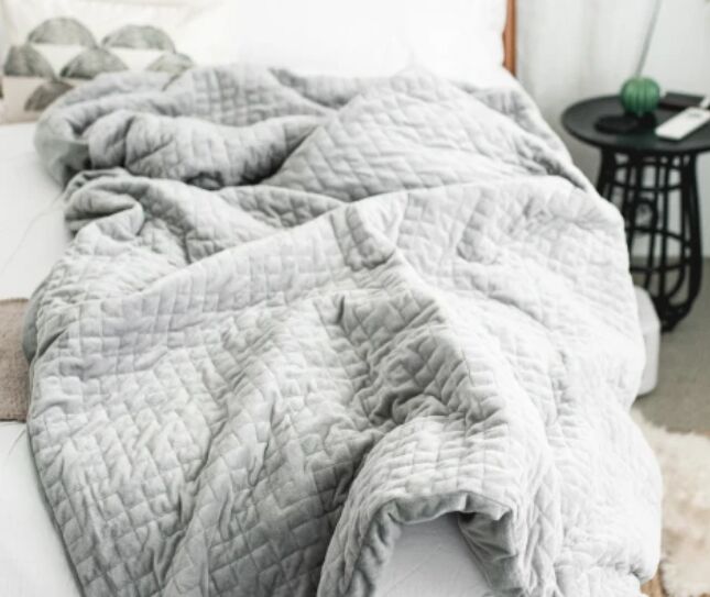 las 7 mejores mantas trmicas para confortar a los que duermen con calor, una manta gris claro cubierta sobre un sof con una mesa negra al fondo
