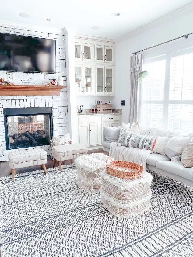 how to paint a stone fireplace for a breathtaking transformation, living room with a painted stone fireplace gray couch striped chairs white cabinets and various patterned textiles