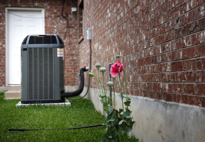 como limpar um filtro de ar condicionado em 6 passos simples, condicionador de ar ao ar livre ao lado de uma parede de tijolos e um jardim com uma flor rosa