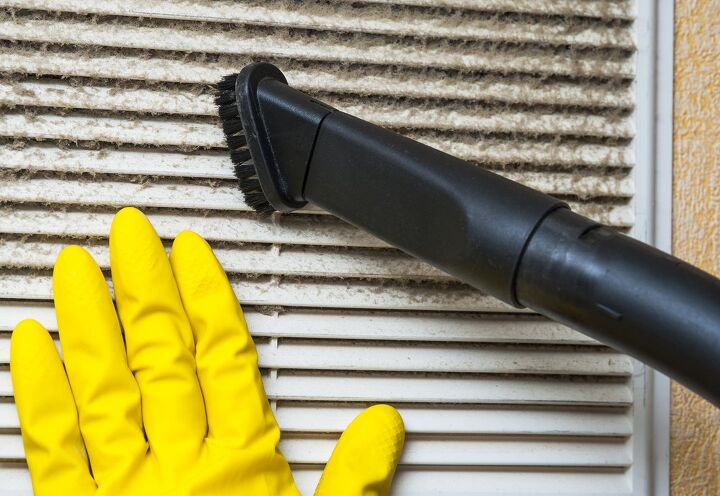 cmo limpiar un filtro de aire acondicionado en 6 sencillos pasos, una mano amarilla con guantes de goma sostiene un filtro de aire acondicionado que se est aspirando con un cepillo