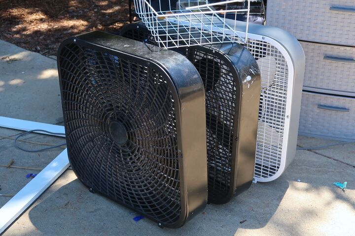 how to clean a box fan, two black box fans and one white box fan lined up on a sidewalk