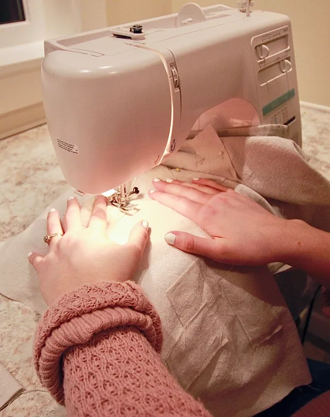 how to thread a sewing machine, hands moving fabric through a sewing machine
