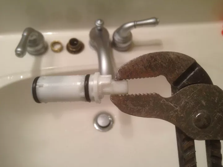 how to fix a leaky faucet before it makes a dent on your water bill, wrench holding white cartridge