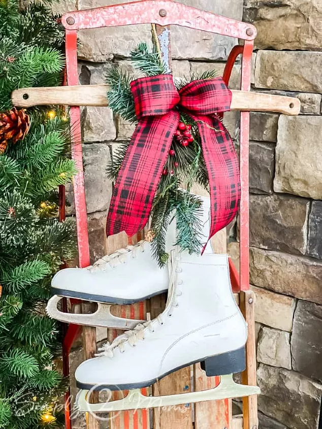 how to make a christmas bow, red plaid Christmas bow on top of decorative sled and ice skates