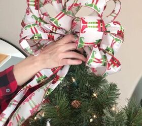 cmo hacer un lazo de navidad de 3 maneras diferentes, Colocaci n a mano de un gran lazo navide o con estampado de elfos en la parte superior del rbol