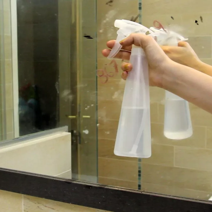 como limpar um espelho perfeitamente sem riscos, m o pulverizando um frasco de spray transparente no espelho sujo