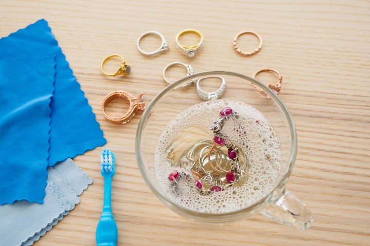 how to clean gold jewelry so it shines like new, gold jewelry soaking in soapy water with surrounding rings and toothbrush