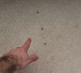 how to fix squeaky floors 3 different ways, hand pointing at screws in white carpet