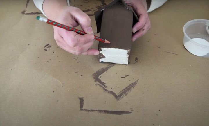 the easiest milk carton gingerbread house in a few steps, Using a pencil to sketch an outline of doors and windows on the milk carton house