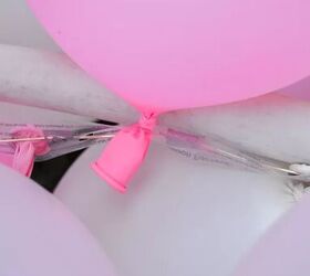 cmo hacer una guirnalda de globos para subir de nivel en tu prxima fiesta, Globo rosa enhebrado a trav s de un agujero de tira de decoraci n de globos
