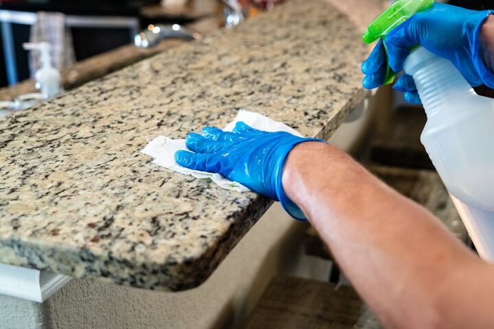 how to clean and care for quartz countertops, rubber gloved hand wiping down quartz countertop