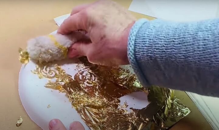 how to make an adorable tie dye paper plate ornament craft, Removing excess gold leaf with a lambs wool roller