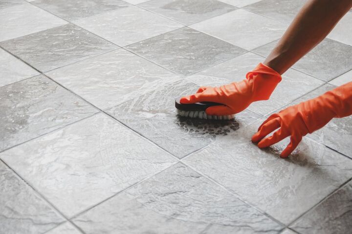 how to remove paint from tile, gloved hands scrubbing floor tiles