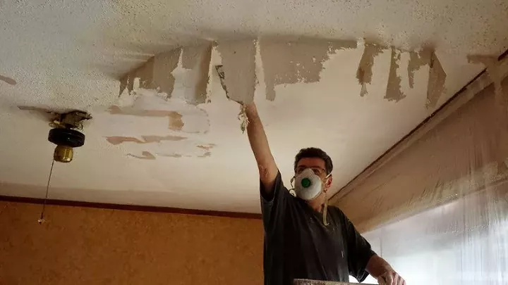 how to remove popcorn ceiling and when you shouldn t try it yourself, man wearing mask removes popcorn ceiling