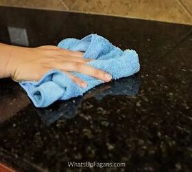 how to clean and disinfect granite countertops, hand wiping down granite countertop with blue towel