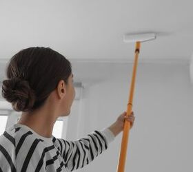 how to clean high ceilings that are nearly impossible to reach, woman cleaning ceiling using long paint roller
