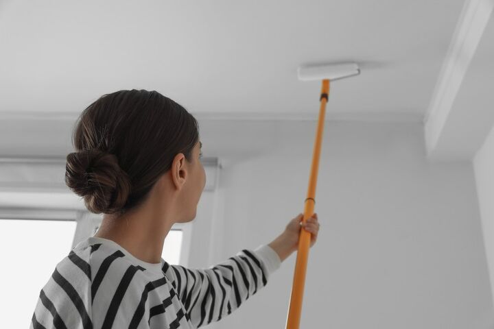 how to clean high ceilings that are nearly impossible to reach, woman cleaning ceiling using long paint roller