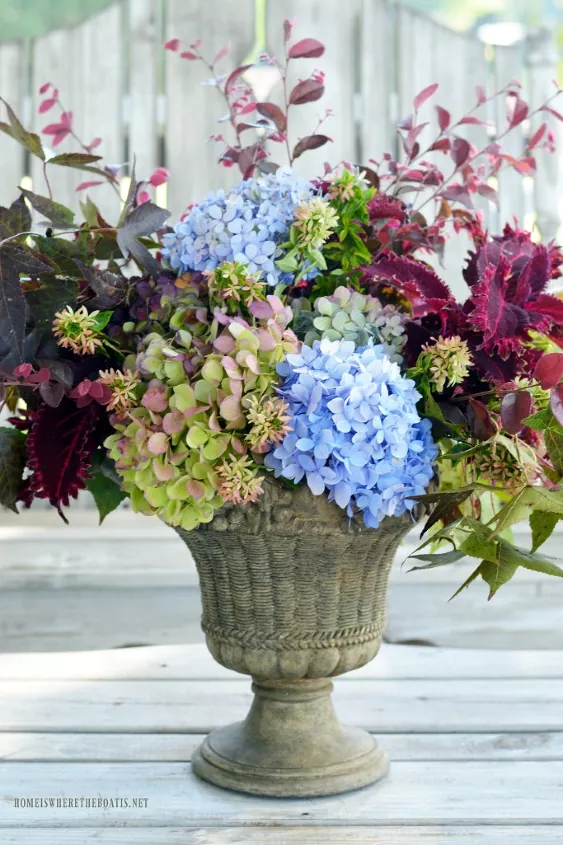 how to arrange flowers in a tall vase, flower arrangement in stone urn with hydrangeas