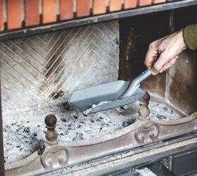 how to clean a wood burning fireplace with ease, hand using scoop to take ash out of fireplace