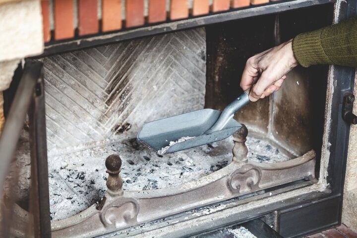 how to clean a wood burning fireplace, hand using scoop to take ash out of fireplace